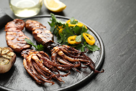 Tasty cooked squids served with garlic and salad on black table, closeupの写真素材