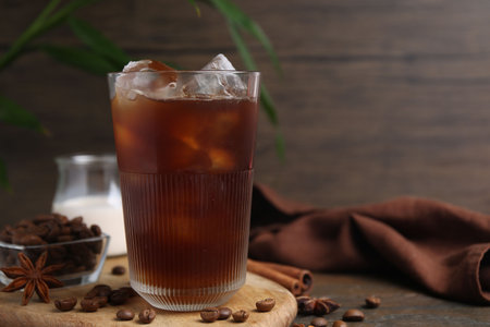Tasty iced coffee in glass and beans on wooden table, closeup. Space for textの写真素材