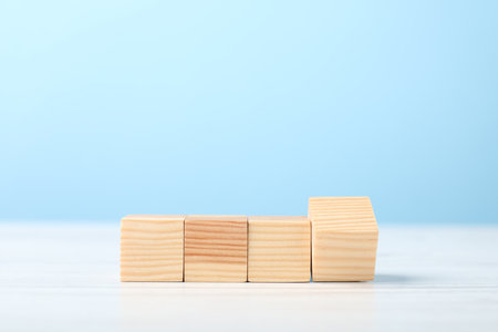Blank cubes on white wooden table against light blue background, space for textの写真素材