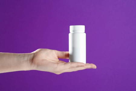 Woman with bottle on purple background, closeupの写真素材