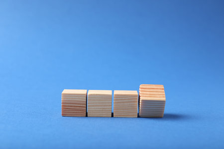 Blank wooden cubes on blue background, space for text