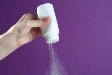 Woman with talcum powder on purple background, closeup. Space for text