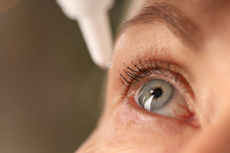 Woman applying eye drops on blurred background, closeupの写真素材