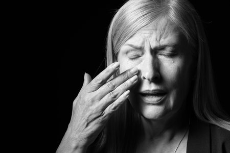Senior woman crying on dark background. Black and white effectの写真素材