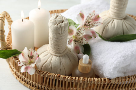 Beautiful spa composition with herbal bags and burning candles on white table, closeupの写真素材