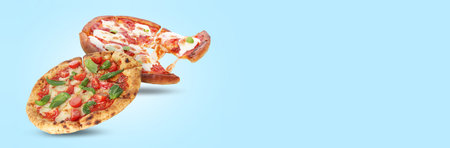 Different delicious pizzas in air on light blue background. Banner design with space for textの写真素材