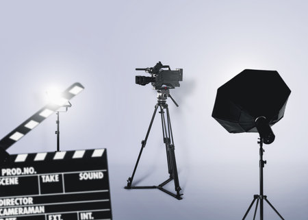Cinema production. Movie clapperboard, professional camera and spotlights in studio