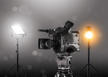 Cinema production. Professional camera and spotlights against gray backgroundの写真素材