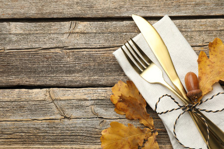 Beautiful table setting. Cutlery with napkin and autumn decor on wooden background, top view. Space for textの写真素材