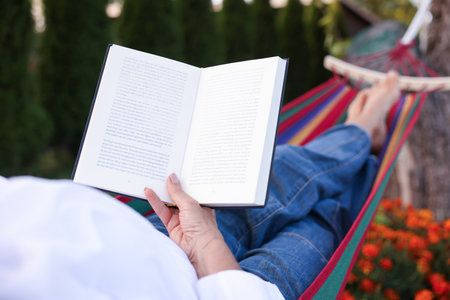 Senior woman with book resting in hammock outdoors, closeupの写真素材