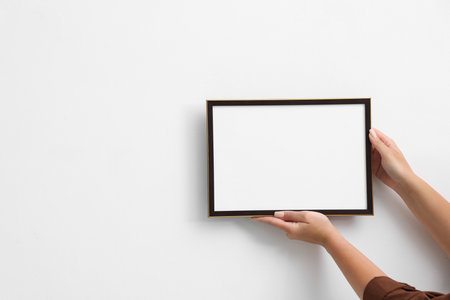 Woman diploma blank frame on white wall, hanging closeup. Mockup for designの写真素材