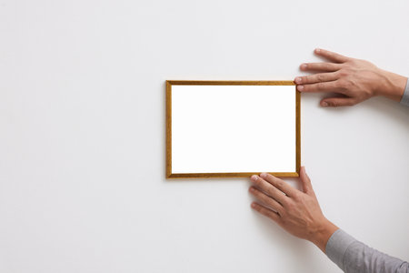 Blank frame on white wall, hanging closeup. Mockup for designの写真素材