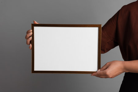 Woman with blank frame on light gray background, closeup. Mockup for designの写真素材