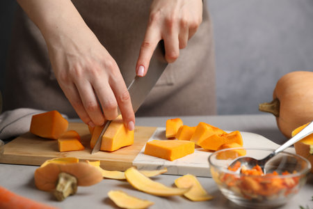 Woman cutting pumpkin at gray table, closeupの写真素材