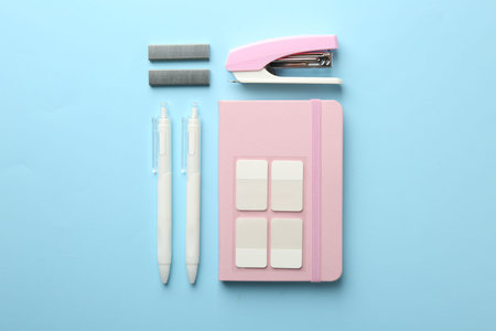 Stapler and other stationery on light blue background, flat lay