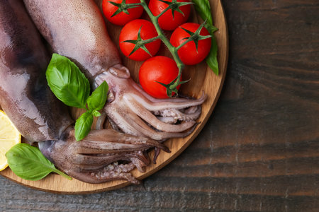 Raw squids, tomatoes and basil on wooden table, top view