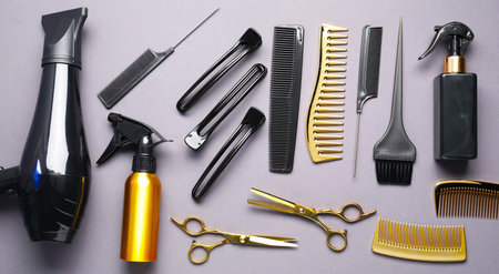 Different hair styling tools on gray background, flat lay