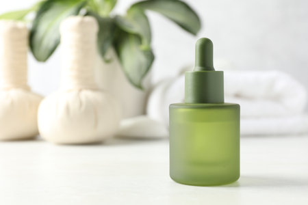 Essential oil, herbal bags, towel and houseplant on light table, selective focus. Spa compositionの写真素材