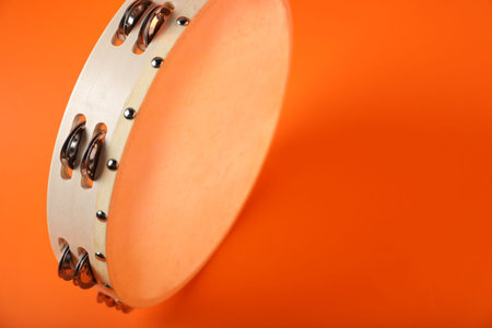 Tambourine on orange background, closeup. Space for textの写真素材
