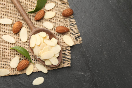 Fresh almond flakes, whole nuts and green leaves on gray table, flat lay. Space for textの写真素材