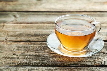Aromatic black tea in glass cup on wooden table, closeup. Space for textの写真素材