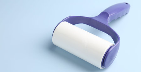 One lint roller on light blue background, closeup. Space for textの写真素材