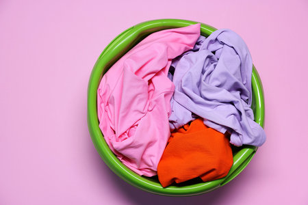 Plastic basin with clothes on pink background, top viewの写真素材