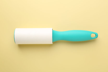 One lint roller on yellow background, top view