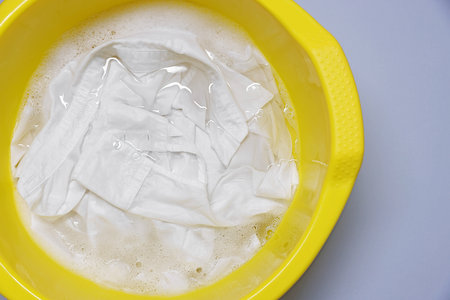 Plastic basin with clothes, water and foam on light gray background, top viewの写真素材