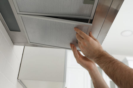 Worker repairing modern cooker hood indoors, closeup