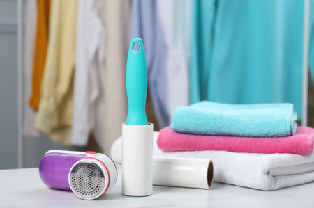 Lint roller, adhesive roll, fabric shaver and stack of towels on white marble table indoorsの写真素材