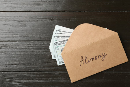 Envelope with word Alimony and money on wooden table, flat lay. Space for textの写真素材