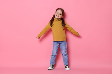 Smiling little girl posing on pink backgroundの写真素材