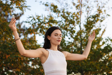 Woman meditating with crystal to heal or restore her aura outdoorsの写真素材