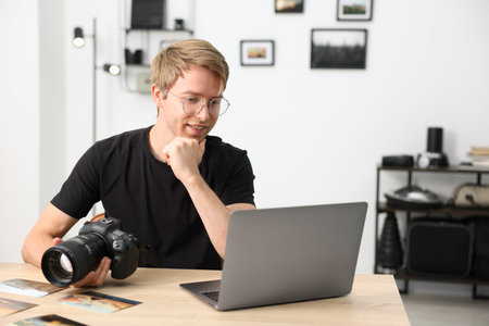 Professional photographer with camera working at table in studioの写真素材