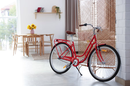 Stylish red bicycle near folding screen indoorsの写真素材