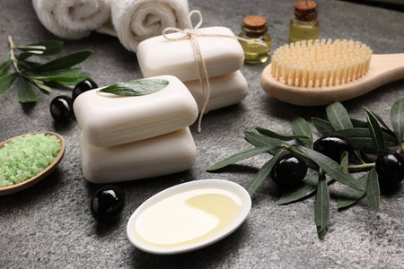 Olive soap bars, oil, sea salt and other bath accessories on gray textured table, closeupの写真素材