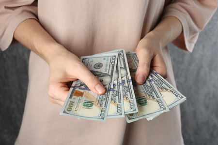 Alimony. Woman with dollar banknotes on gray background, closeupの写真素材