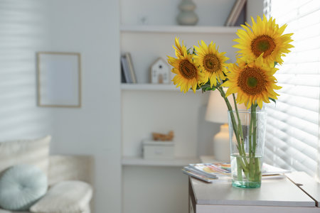 Beautiful sunflowers in vase near window indoors. Space for textの写真素材