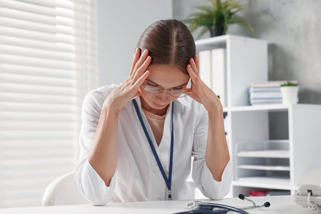Tired nurse at table in clinic. Medical workerの写真素材