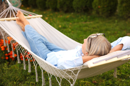 Senior woman resting in comfortable hammock outdoorsの写真素材