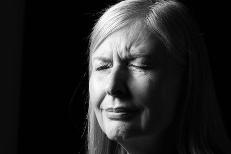 Senior woman crying on dark background, closeup. Black and white effectの写真素材