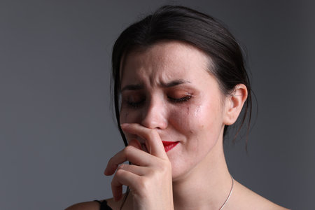 Woman crying on gray background, closeupの写真素材