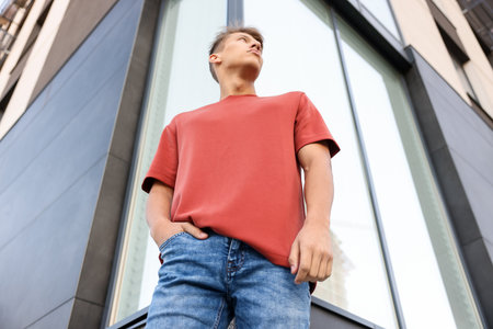 Young man wearing blank red t-shirt outdoors, low angle view. Mockup for designの写真素材