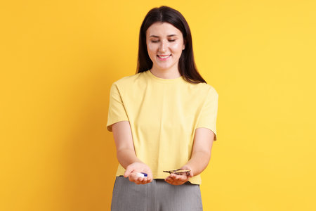 Young woman choosing between glasses and contact lenses on orange backgroundの写真素材