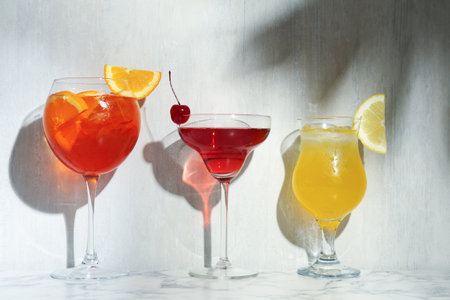Glasses of tasty cocktails with garnish on white marble tableの写真素材