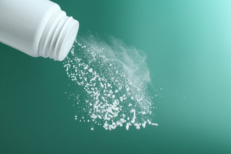 Pouring talcum powder from plastic bottle on green background, closeupの写真素材