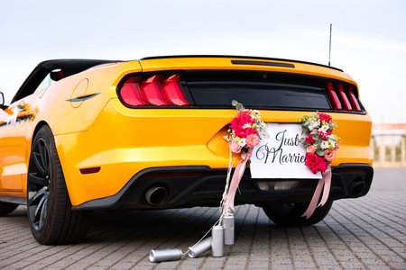 Wedding car. Cabriolet decorated with Just Married card, beautiful flowers and tin cans outdoors,...
