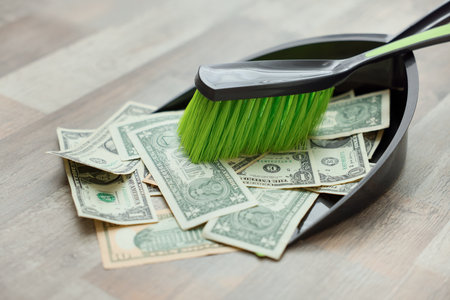 Dollar banknotes, dustpan and broom on floor, closeupの写真素材