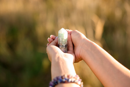 Woman meditating with crystal to heal or restore her aura outdoors, closeup. Space for textの写真素材